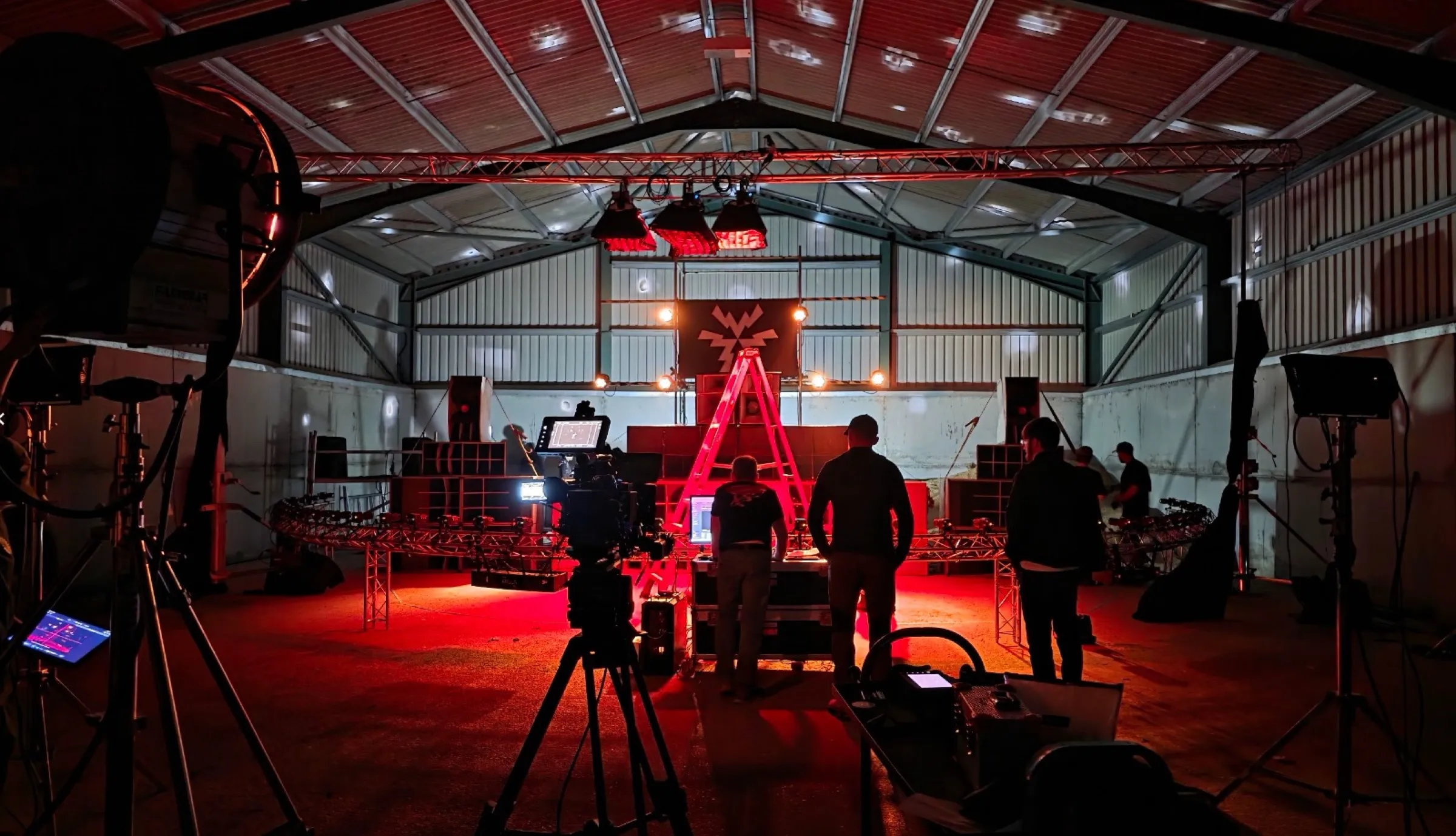 The metal barn at Misbourne Valley lit red for the shoot, with the Argus rig arc, cinema camera and crew setting up