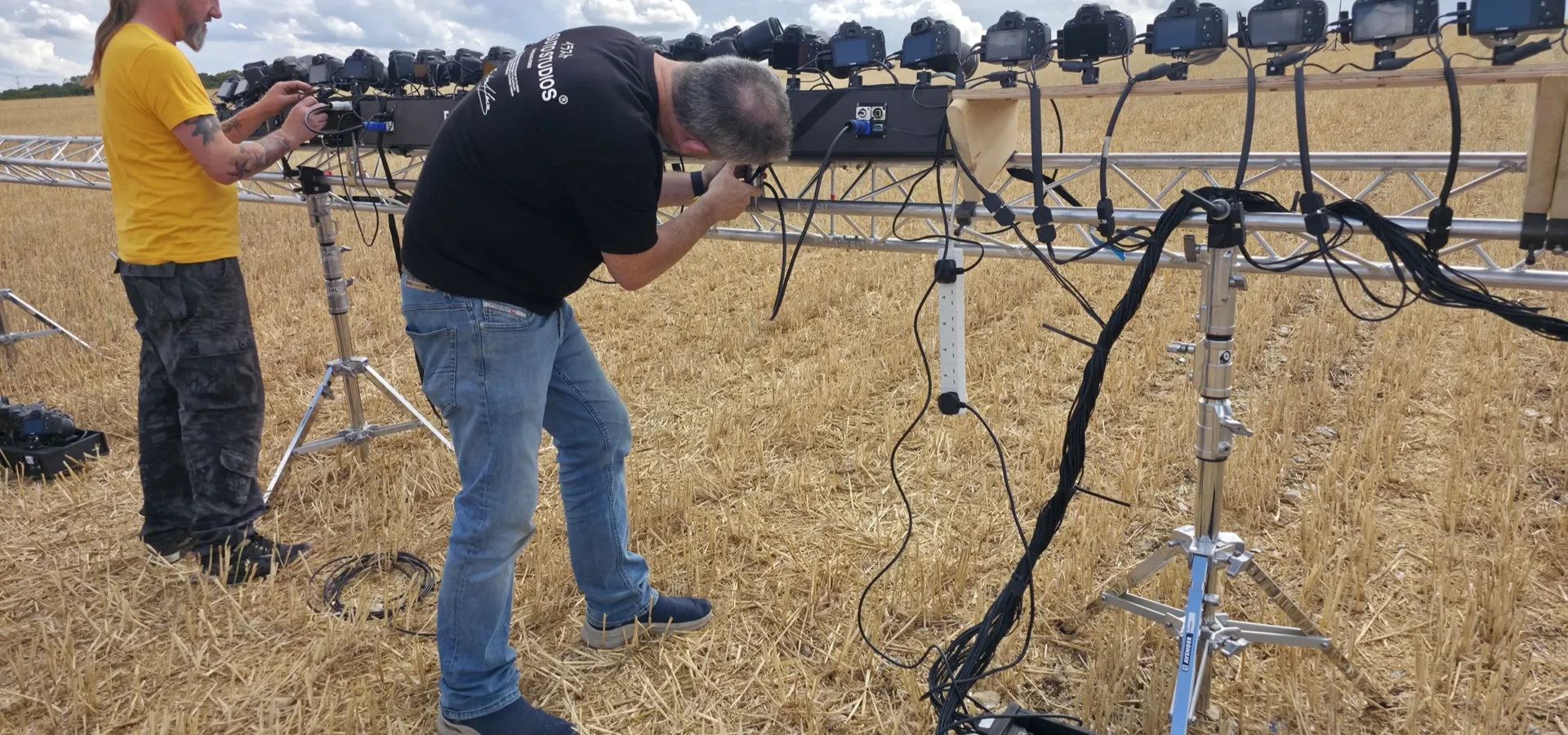 A checkerboard calibration board on a stand in the field, with a crew member walking out to it