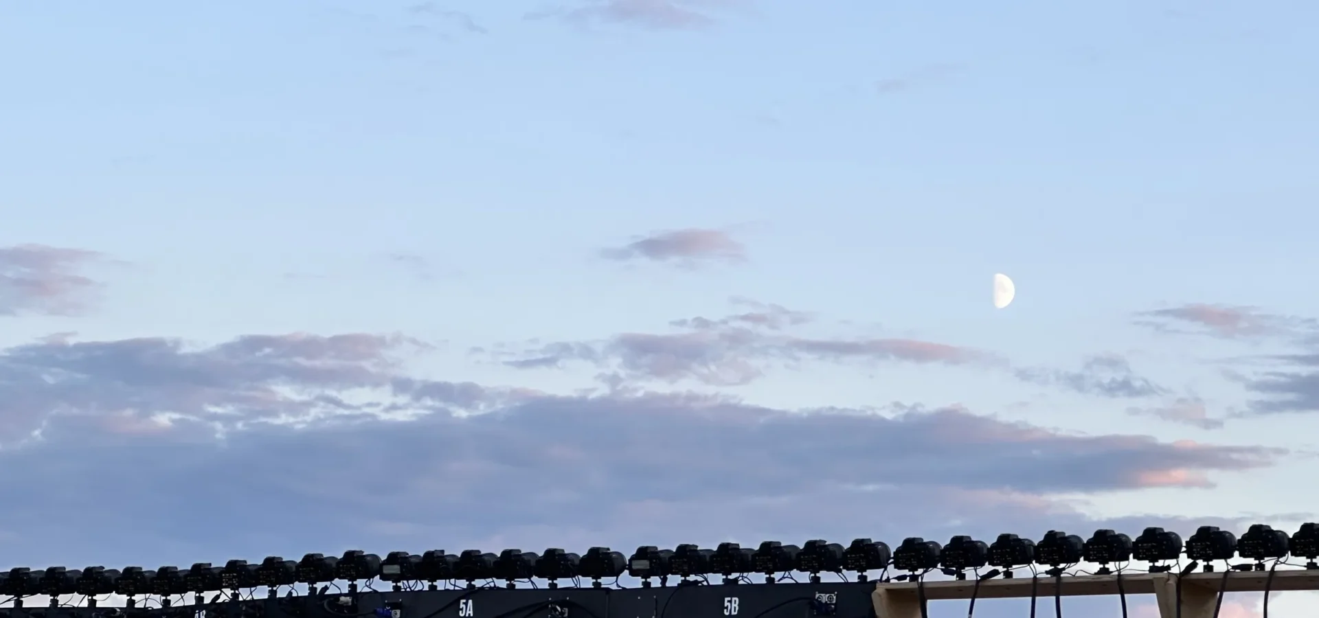 The moon above the row of stills cameras at dusk