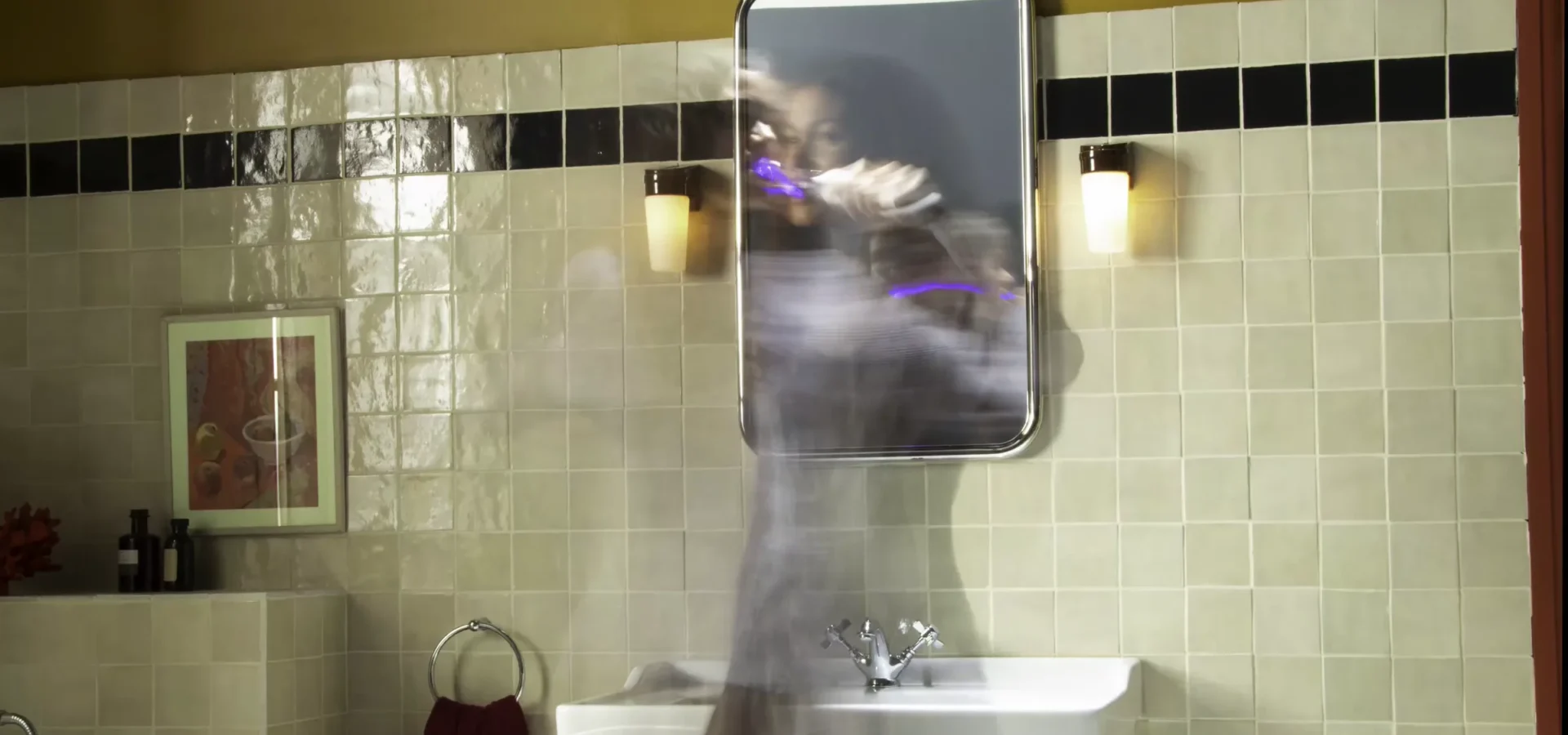Long exposure from the DSLR rig: the talent brushing at the bathroom mirror with the light on the brush trailing